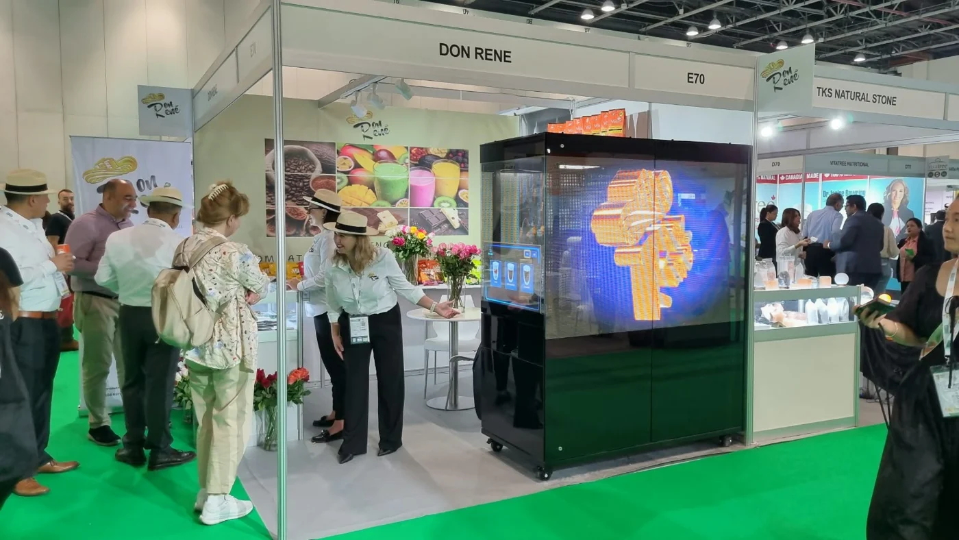Brio robotic coffee kiosk integrated into a branded exhibition stand with visitors nearby